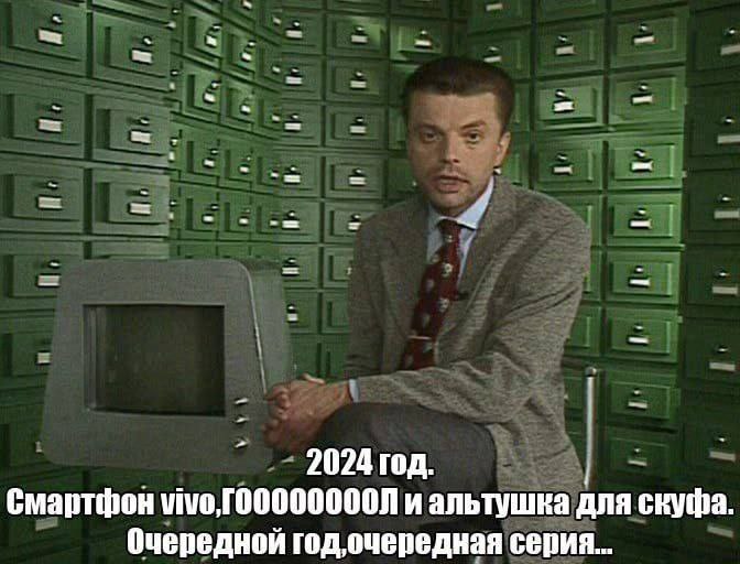 2024 год, очередная серия Мужчина в пиджаке и галстуке сидит на стуле, а рядом с ним стоит старый компьютер. За его спиной стена, полностью состоящая из картотечных ящиков. На изображении также присутствует надпись про 2024 год, смартфон vivo, гооооооооол и альтушку для скуфа.