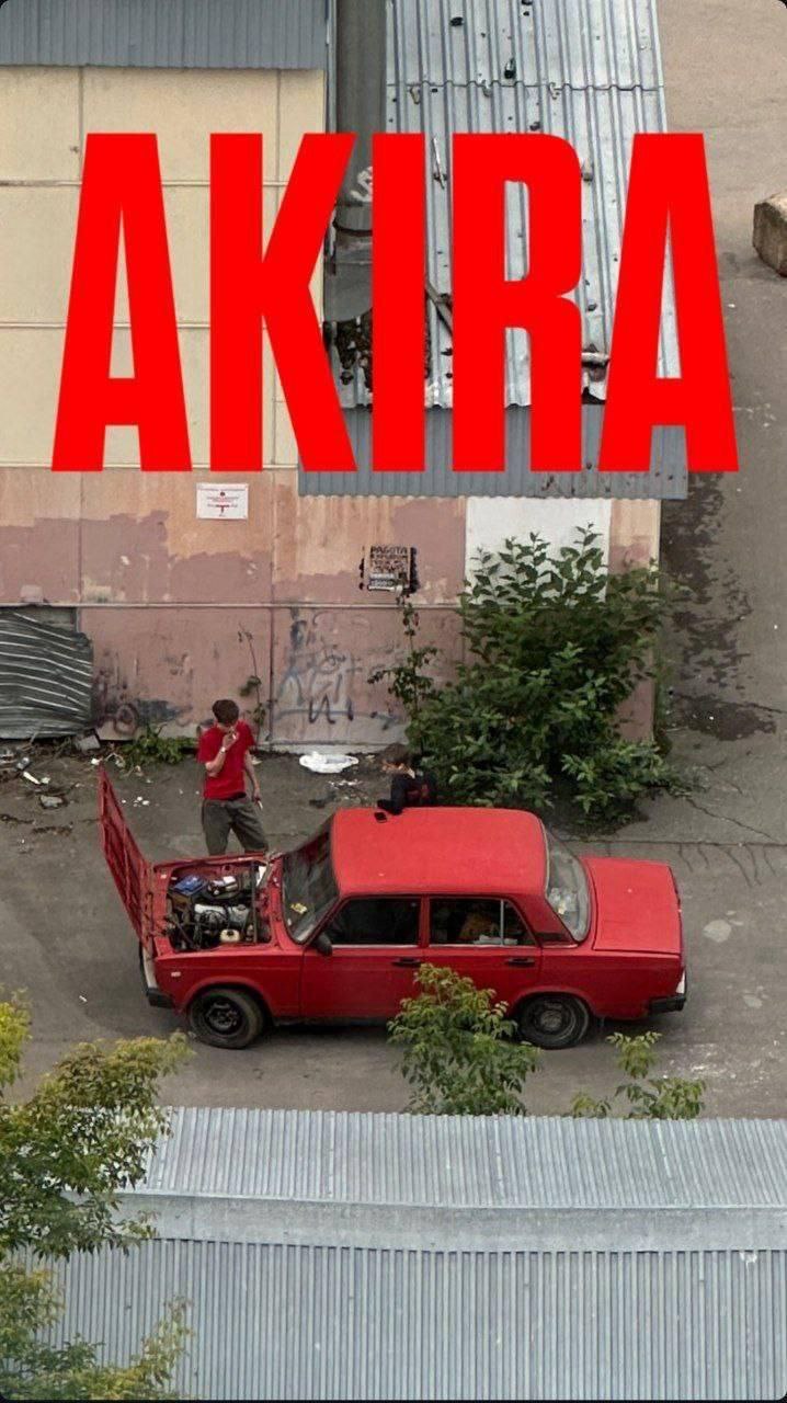 AKIRA Человек чинит красные "Жигули" с надписью AKIRA сверху