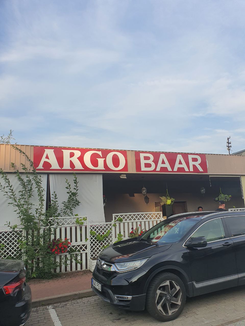 ARGO BAAR Вывеска "ARGO BAAR" на здании, частично скрытая забором и растениями