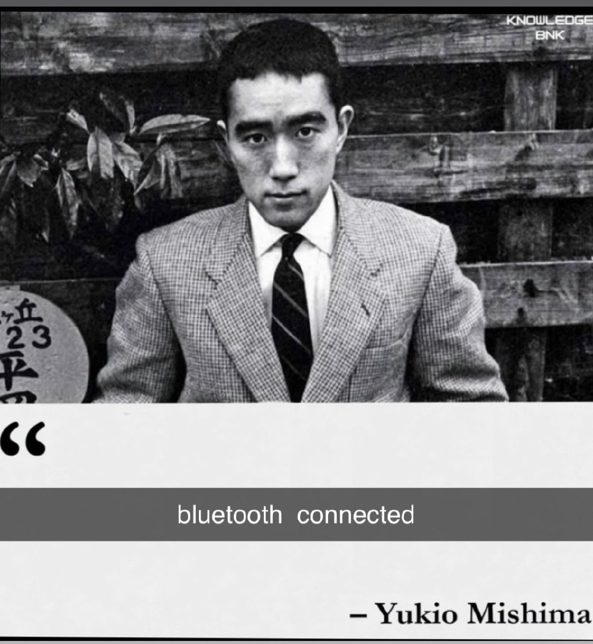Серьезный черно-белый портрет Юкио Мисимы с шуточной цитатой «bluetooth connected» — «Bluetooth подключен».