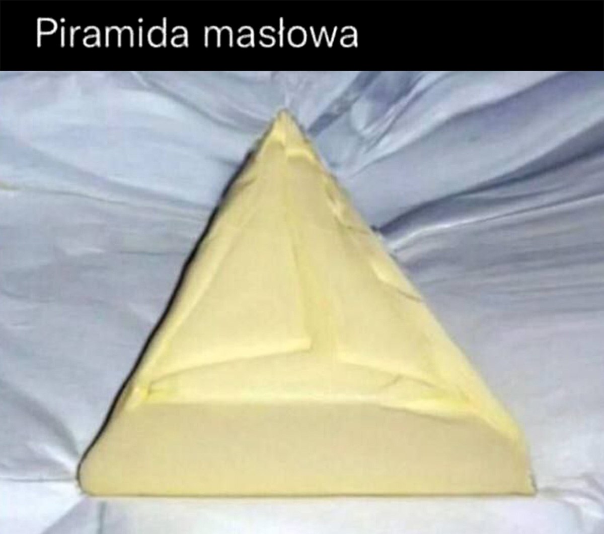 Масляная пирамида Масло в форме пирамиды, лежащее на белой простыне.