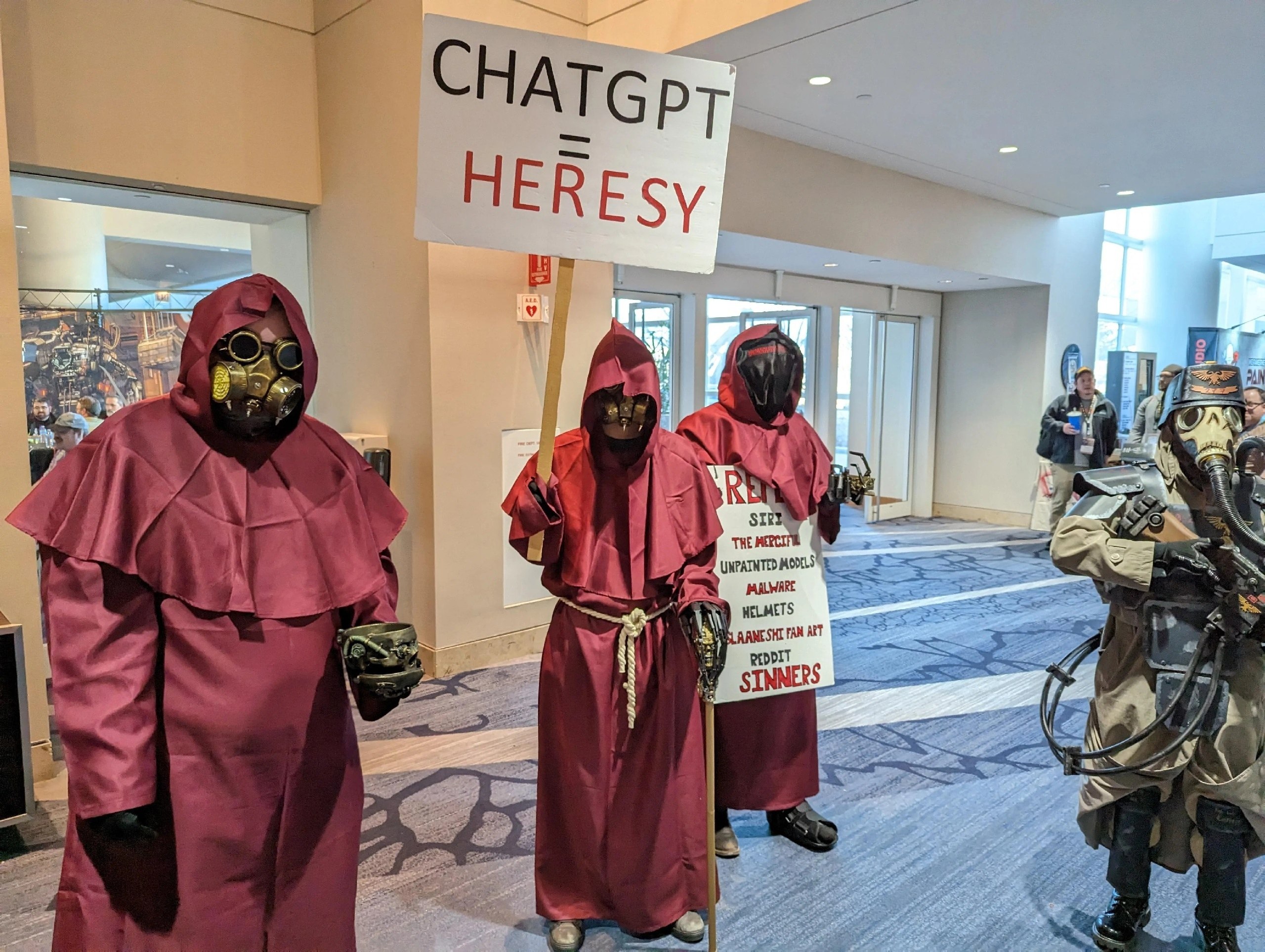 Косплееры, одетые в стиле Warhammer 40,000, протестуют против ChatGPT, держа плакат с надписью «CHATGPT HERESY»