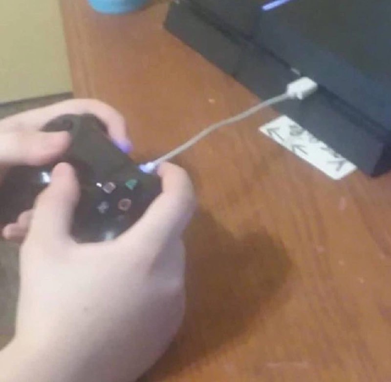 Человек играет в PlayStation 4 Человек играет в PlayStation 4, держа в руках геймпад и подключив его к консоли