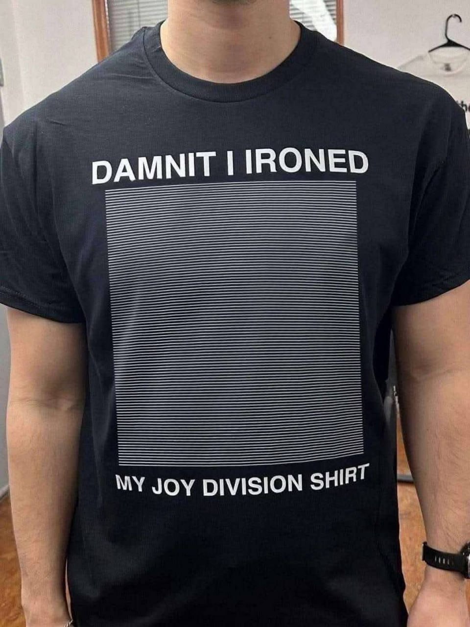 Damnit I ironed my Joy Division shirt Мужчина в черной футболке с надписью «Damnit I ironed my Joy Division shirt» и выглаженным изображением, которое должно было быть сморщенным.
