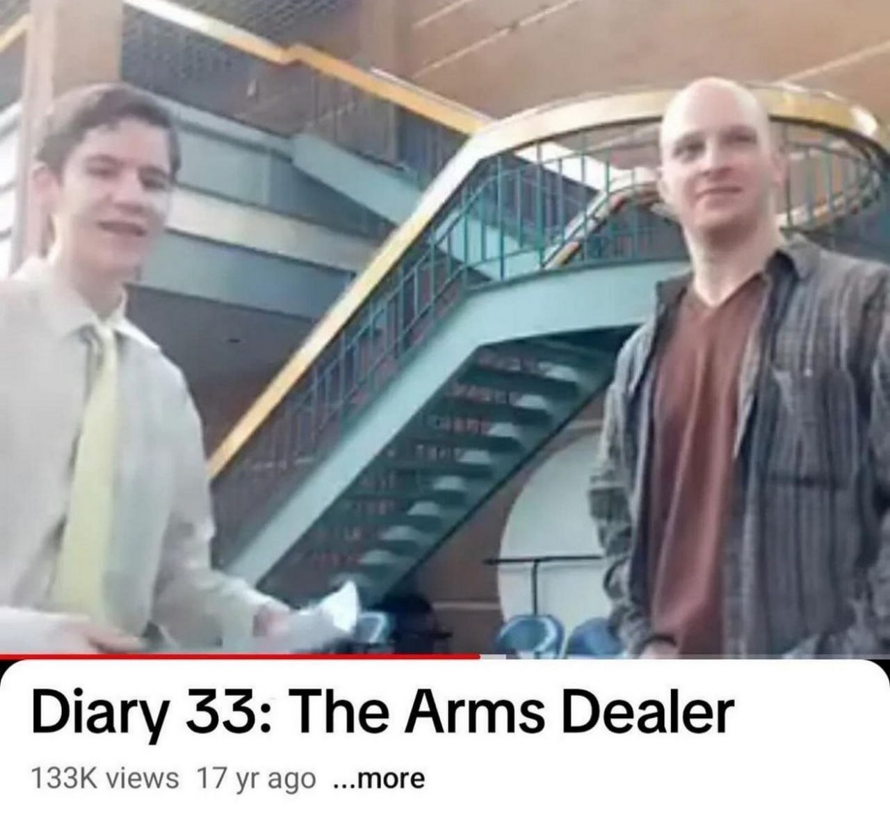 Diary 33: The Arms Dealer Два человека, один из которых держит бумагу, стоят на фоне лестницы, а под ними виден текст "Diary 33: The Arms Dealer" из видеохостинга YouTube.
