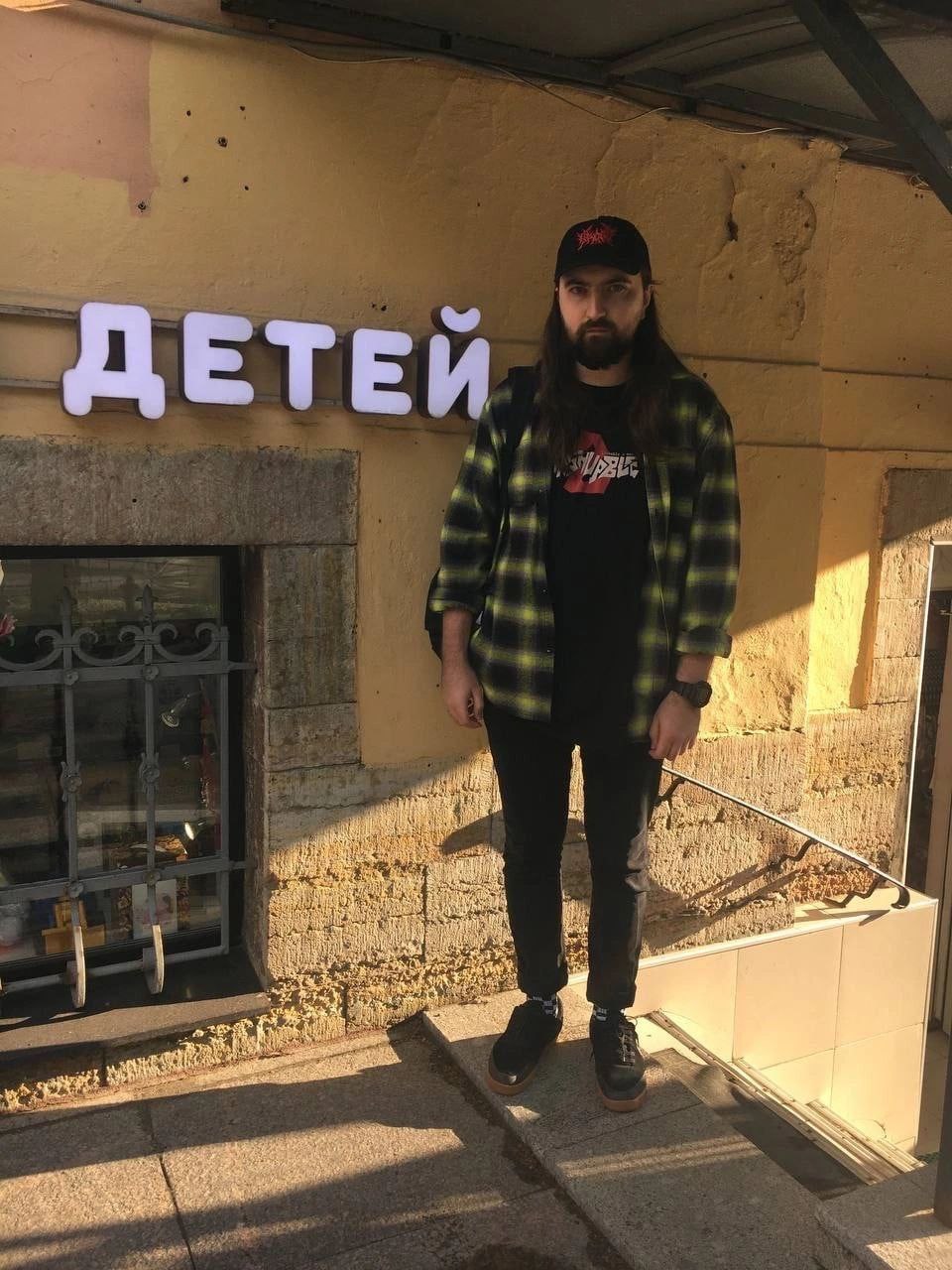 Дима Сыендук и надпись «Детей» Дмитрий Сыендук стоит на улице напротив вывески «Детей»