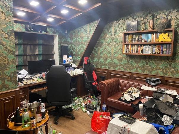 Грязная комната геймера Фотография грязной комнаты геймера с разбросанными бутылками и беспорядком на столе и диване.