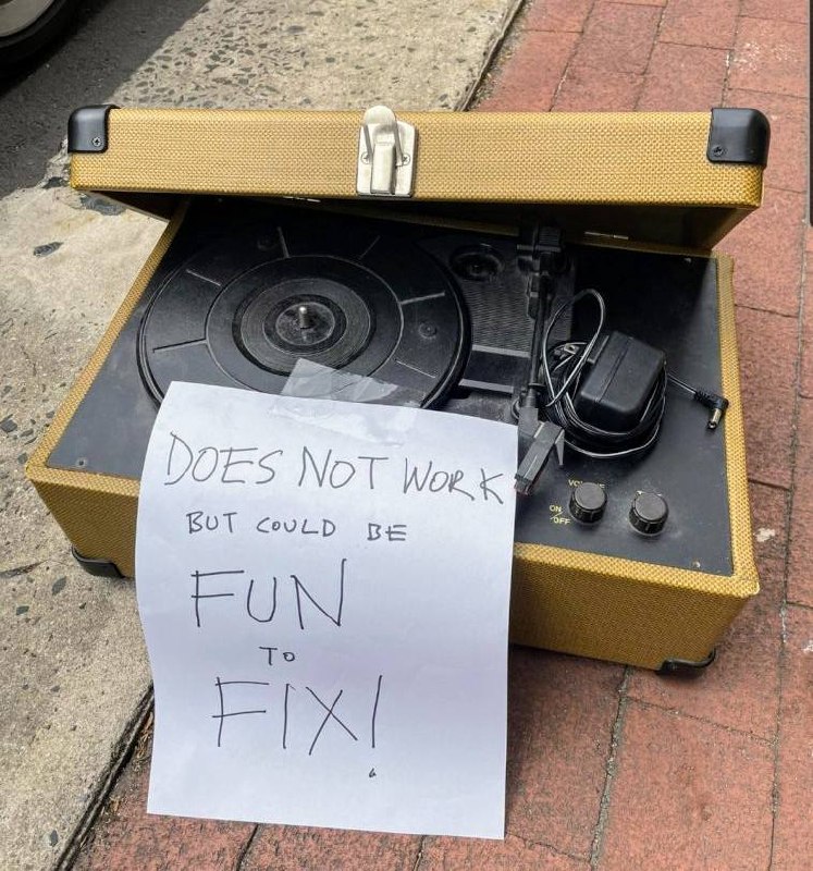 Старый проигрыватель винила с табличкой «Does not work but could be fun to fix!» на тротуаре