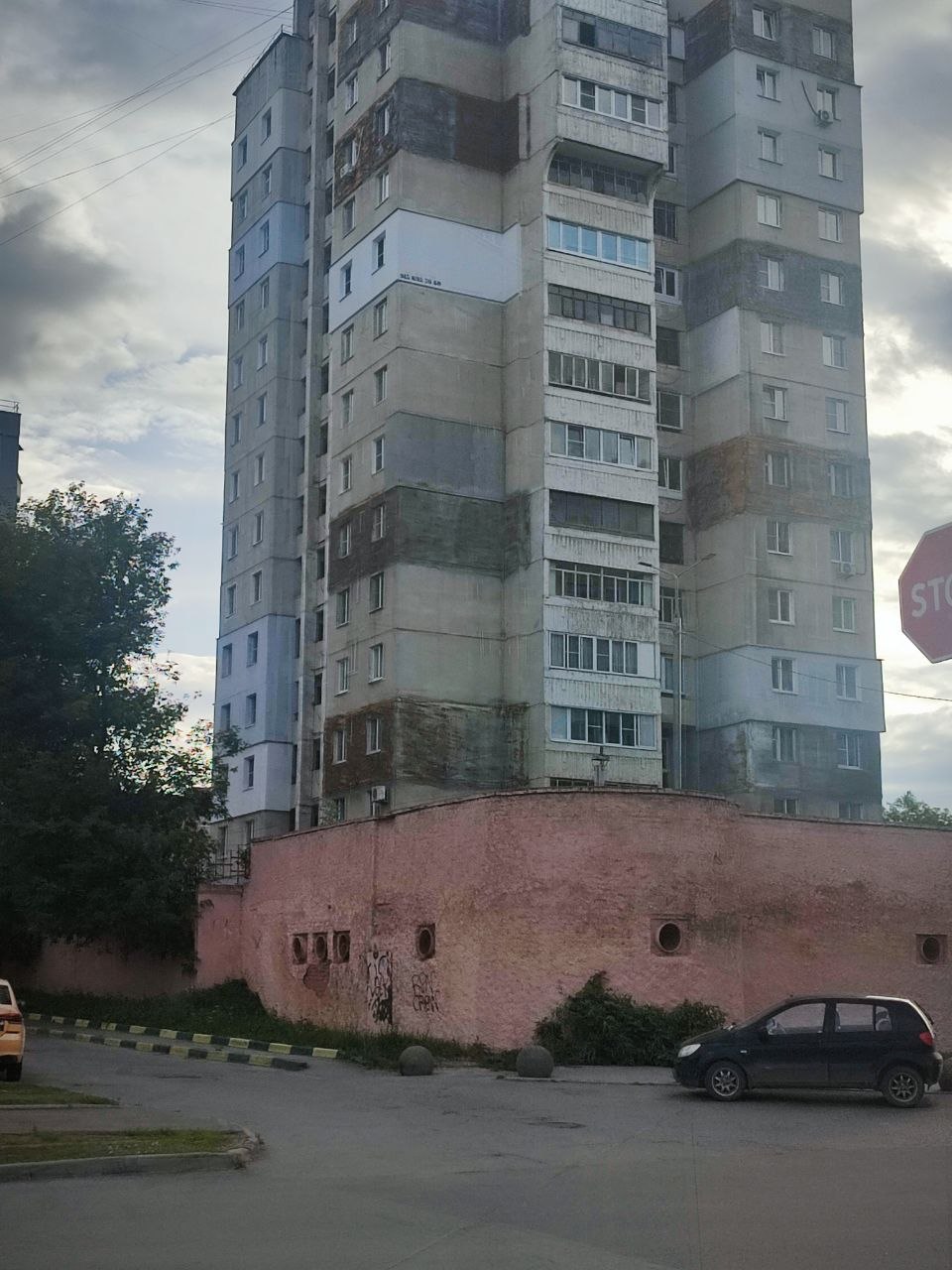 Необычный старый панельный дом с множеством застеклённых балконов и лоджий на фоне пасмурного неба