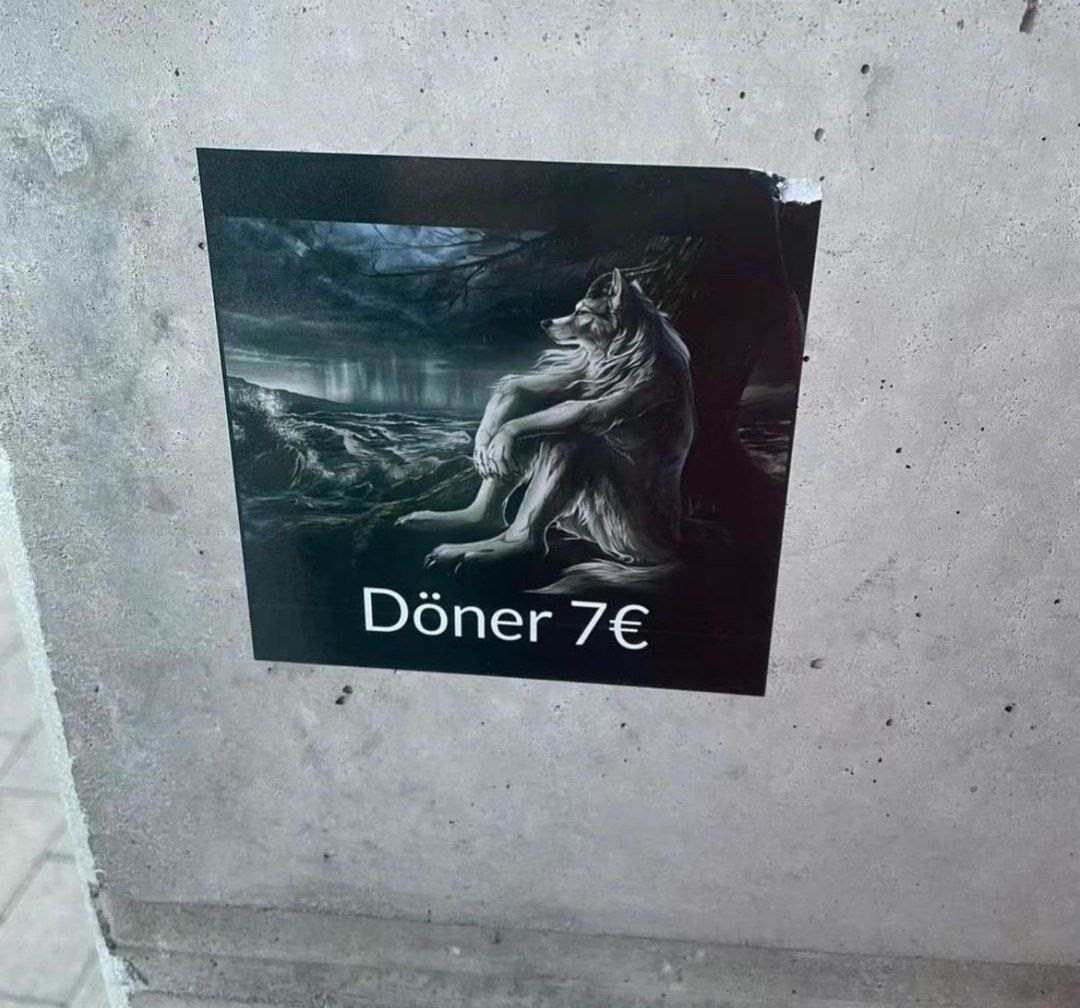 Döner 7€ и грустный волк Плакат с грустным волком и надписью Döner 7€, приклеенный к бетонной стене