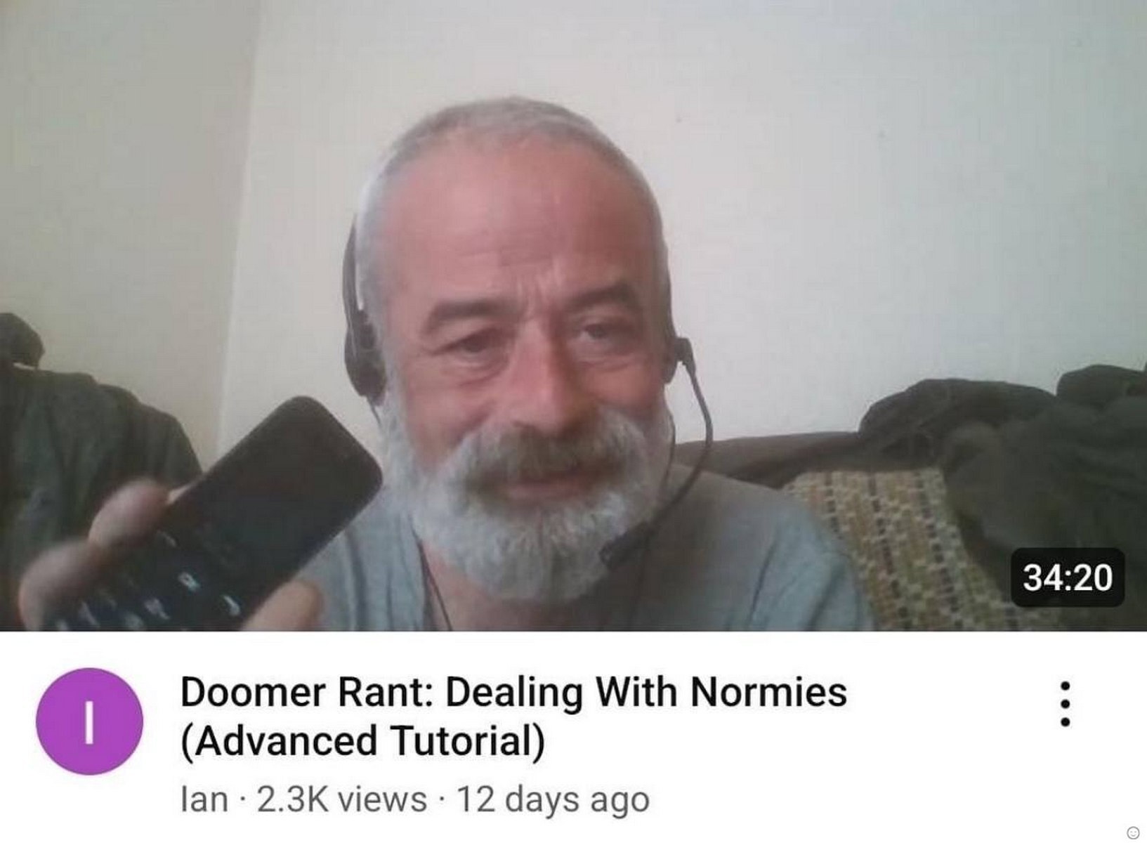 Doomer Rant: Dealing With Normies Пожилой мужчина с седой бородой, в наушниках с микрофоном, держит кнопочный телефон и улыбается на фоне белой стены. Под ним заголовок видео "Doomer Rant: Dealing With Normies (Advanced Tutorial)".