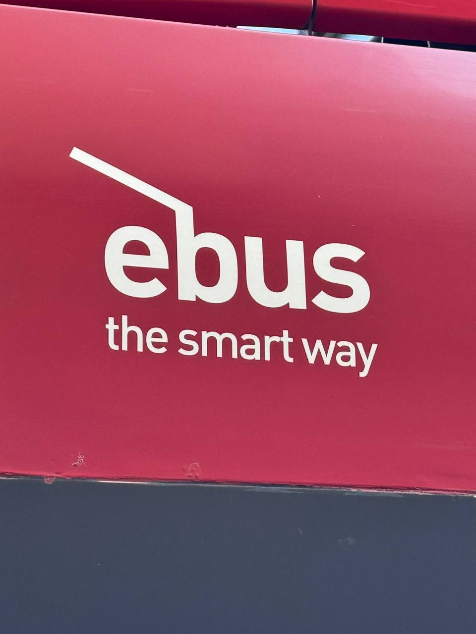 Белый логотип «ebus» и надпись «the smart way» на красном фоне автобуса.