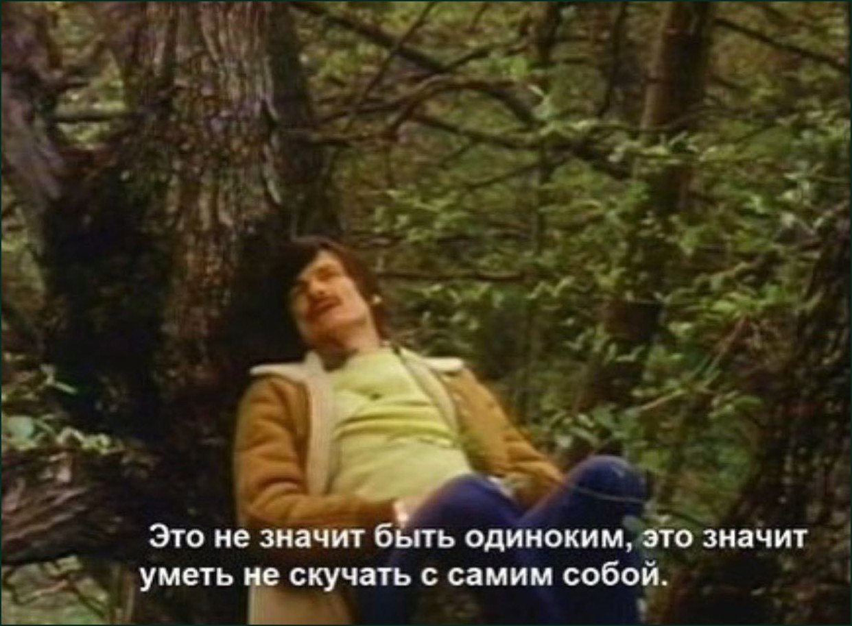 Мужчина отдыхает в лесу с надписью о том, что одиночество — это умение не скучать наедине с собой.