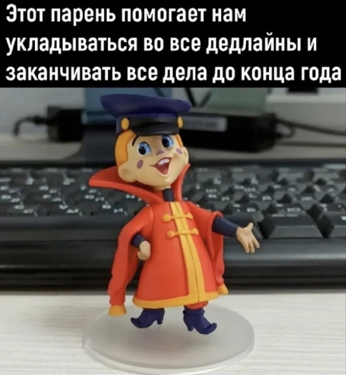 Фигурка мальчика в красном пальто на фоне клавиатуры с надписью о том, что этот парень помогает укладываться во все дедлайны и заканчивать все дела до конца года