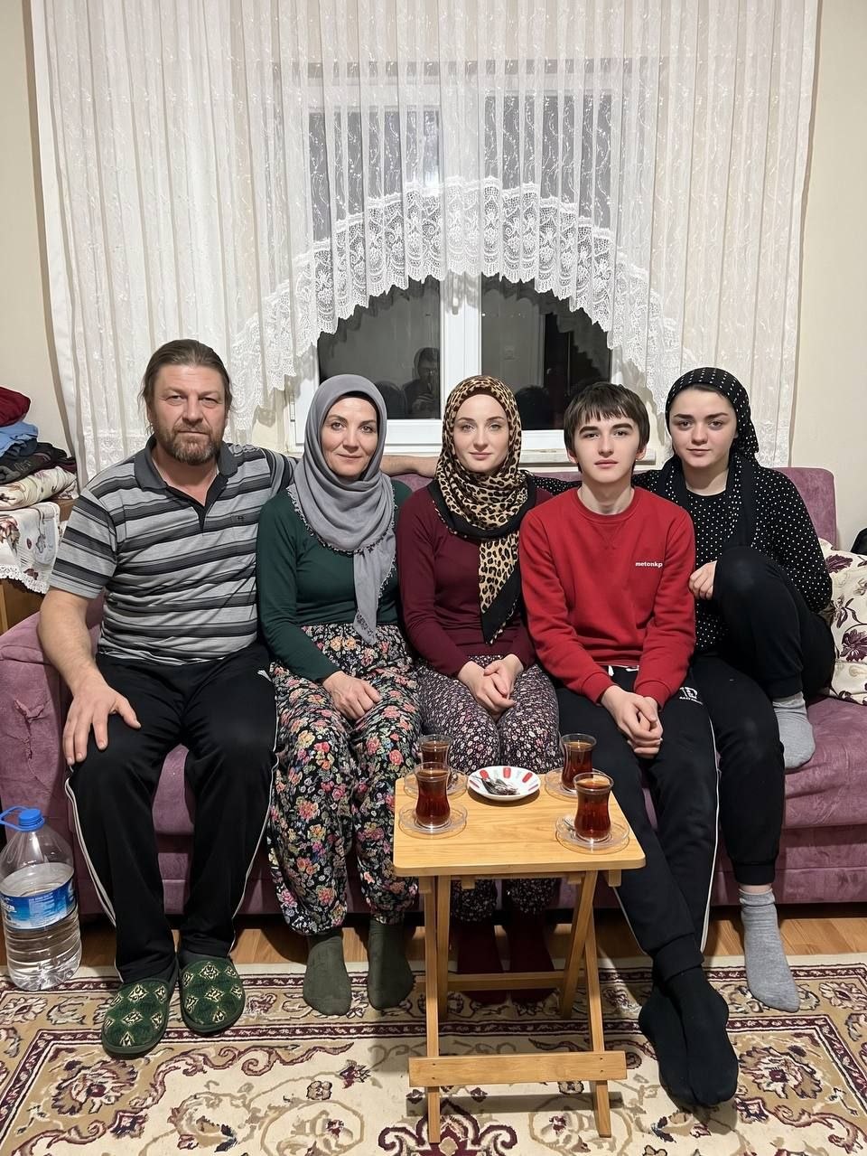 Пятеро родственников сидят на диване за чаем и серьёзно смотрят в камеру на семейной фотографии