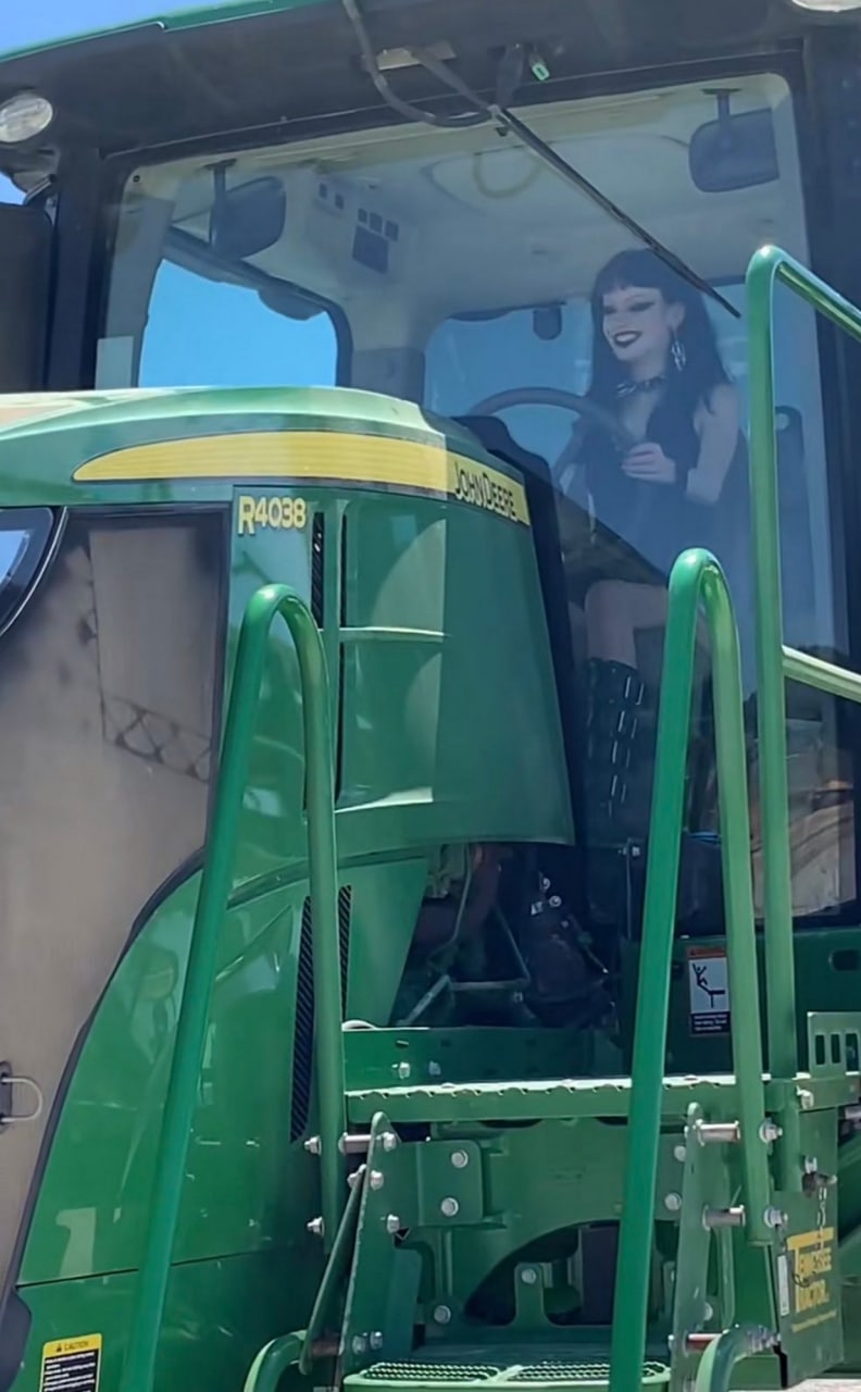 Девушка гот за рулем трактора John Deere Девушка гот за рулем трактора John Deere в солнечный день.