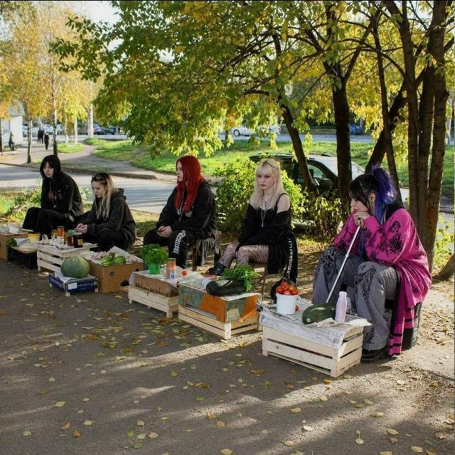 Готы в альтернативной одежде продают овощи с деревянных ящиков на осенней улице