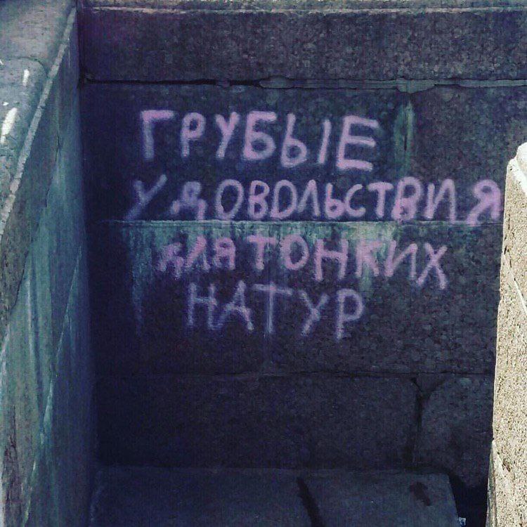 Грубые удовольствия для тонких натур Надпись граффити «Грубые удовольствия для тонких натур» на бетонной стене в темном месте