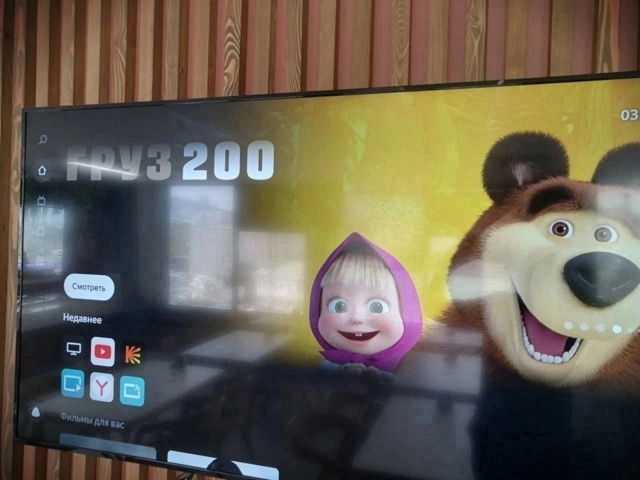 Груз 200 и Маша и Медведь На экране телевизора запущен мультфильм «Маша и Медведь», но на фоне отображается надпись «Груз 200» и меню приложения.