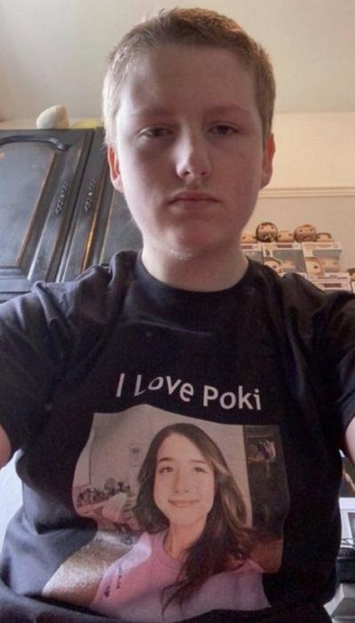 Парень в футболке I love Poki Мем, на котором изображен подросток с бледным лицом, в черной футболке с надписью «I Love Poki» и фотографией девушки в розовой кофте. На заднем плане видна мебель и коллекция виниловых фигурок Funko Pop.