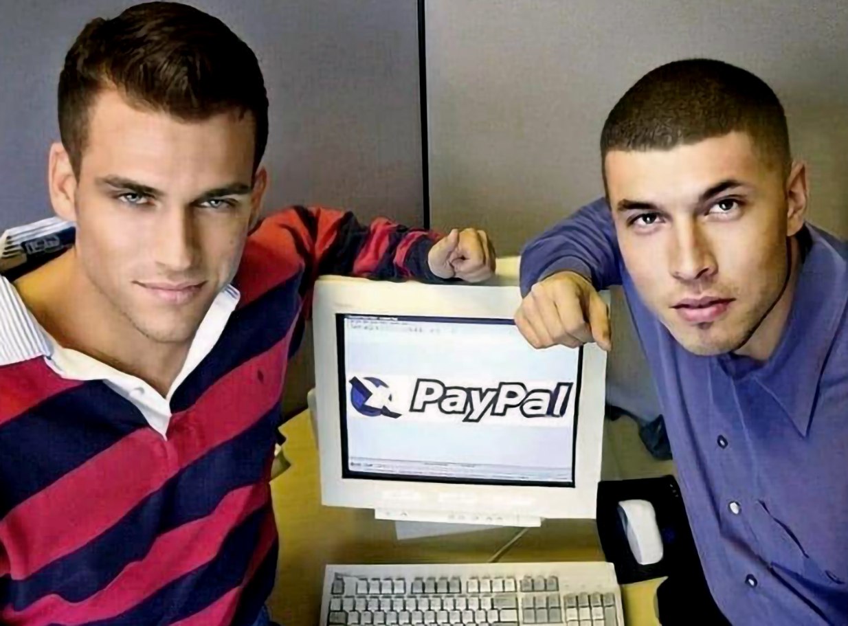 Парни с монитором PayPal Двое молодых парней стоят рядом со старым монитором, на экране которого отображён логотип PayPal.