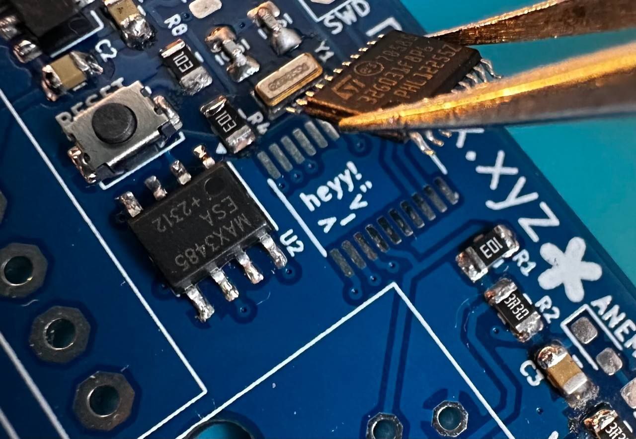 Надпись "heyy! >_v" на чипе, который держит пинцет