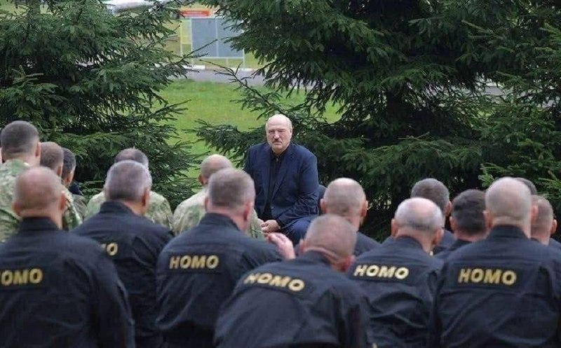 Мужчина сидит перед группой людей в форме с надписью «HOMO» на спинах