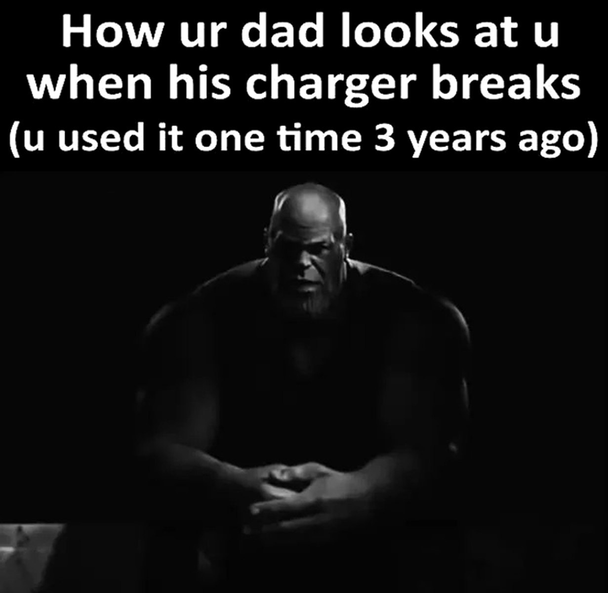 How ur dad looks at u when his charger breaks Как твой папа смотрит на тебя, когда его зарядка ломается, а ты пользовался ею один раз 3 года назад. На черно-белой картинке изображен Танос из вселенной Марвел, он сидит на корточках, сложив руки на коленях, и смотрит вдаль, будто разочарованно или угрожающе.