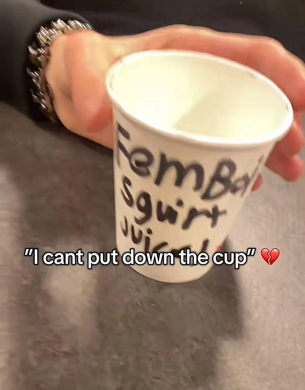 I cant put down the cup Рука держит стаканчик с надписью «FemBoy squirt juice», а снизу подпись «I cant put down the cup» и разбитое сердце.