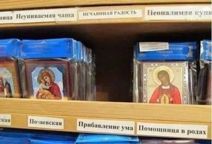 Иконы в магазине с надписями Фотография полок в магазине с православными иконами, где под каждой иконой написаны ее названия, такие как «Неупиваемая чаша», «Прибавление ума», «Помощница в родах».