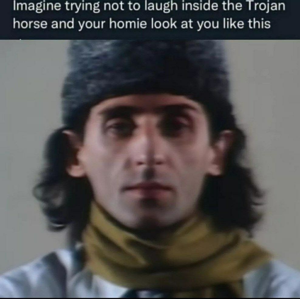 Imagine trying not to laugh Мем с мужчиной в черной меховой шапке и желтом шарфе, смотрящим прямо перед собой с серьезным выражением лица.
