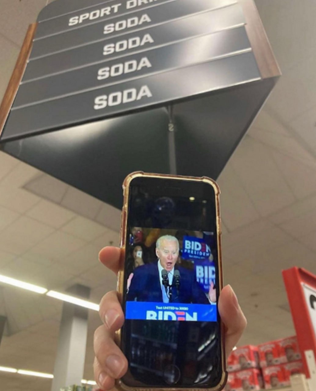 Джо Байден и "SODA" на ценнике Джо Байден на экране телефона и указатель с надписями "SODA" в магазине
