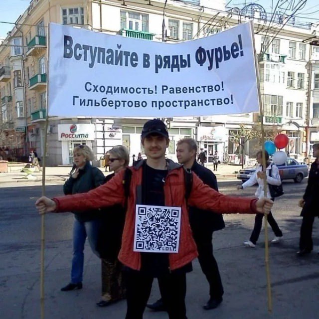 Мужчина с плакатом "Вступайте в ряды Фурье" и QR-кодом на груди