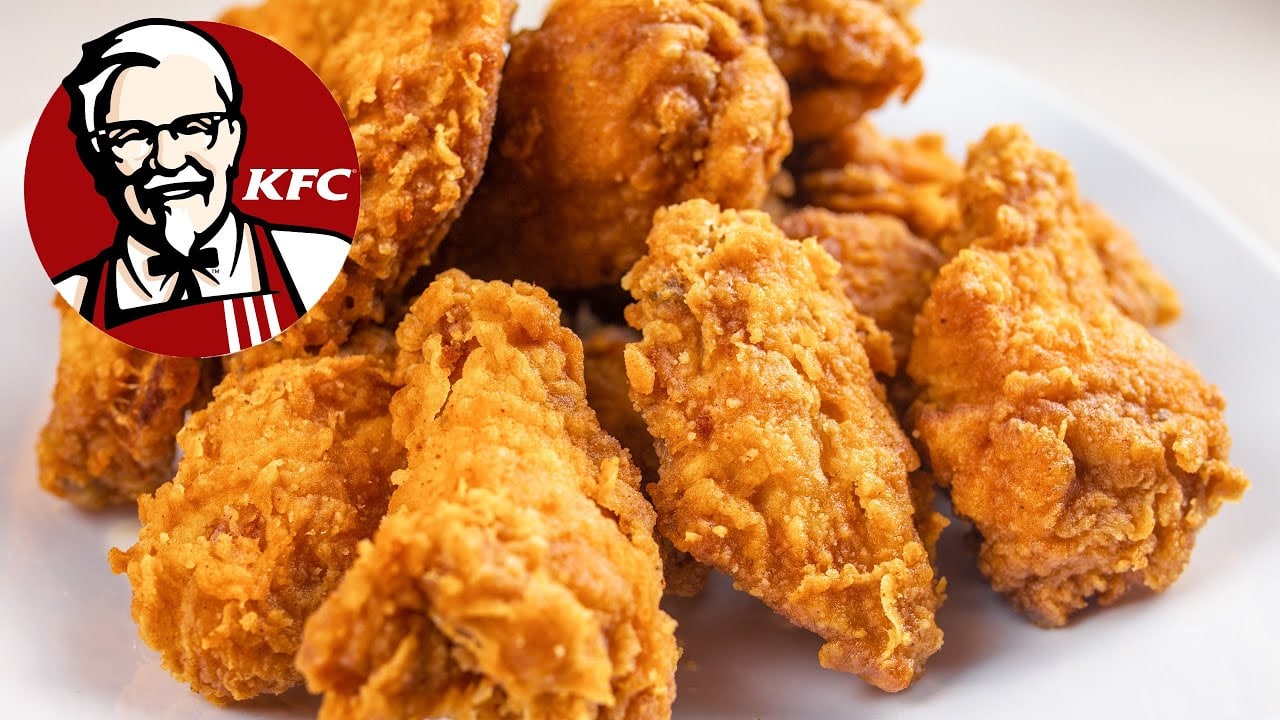 Куриные крылышки KFC на тарелке Куриные крылышки KFC в панировке на белой тарелке с логотипом полковника Сандерса