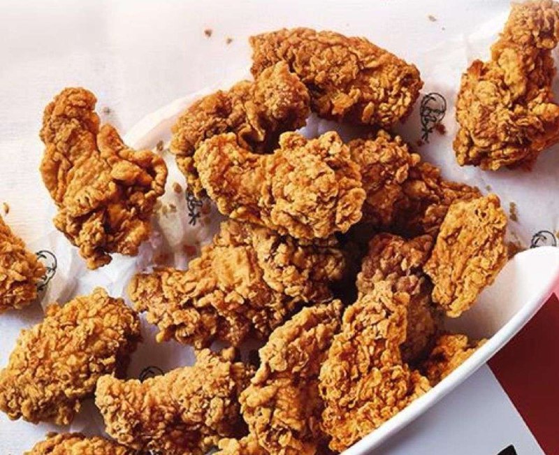 KFC хрустящие стрипсы Крупный план хрустящих куриных стрипсов KFC на белой бумаге с логотипами