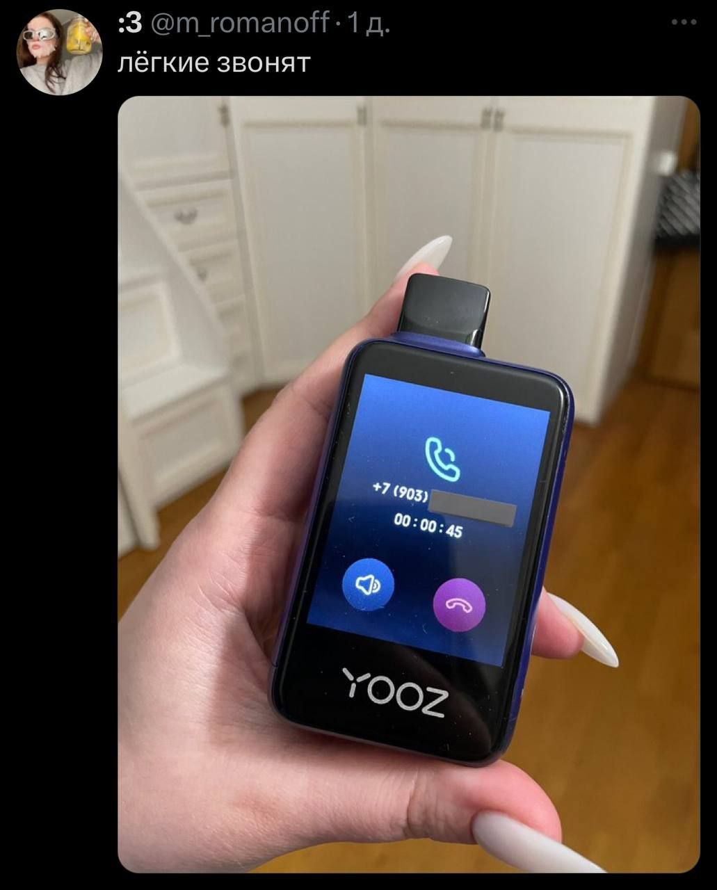 Лёгкие звонят Девушка держит в руке электронную сигарету Yooz, на экране которой отображается входящий звонок с текстом "Лёгкие звонят".