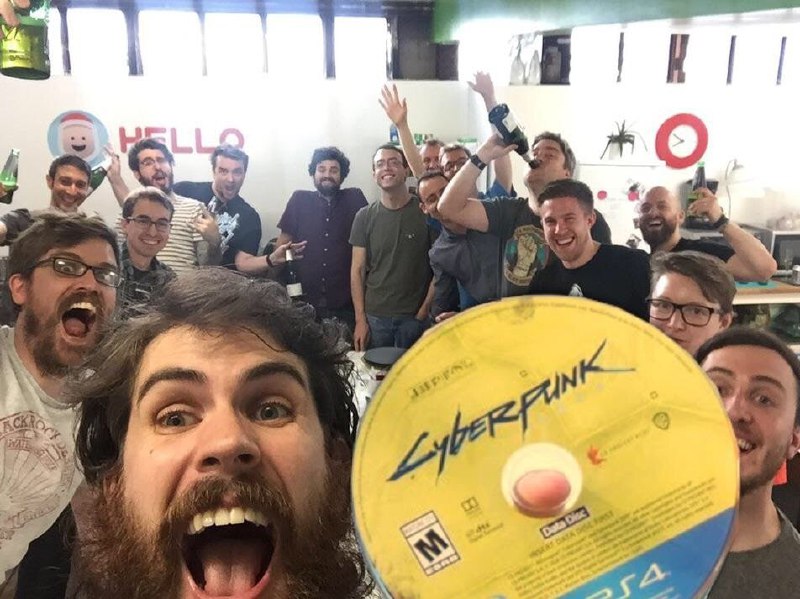 Люди с диском Cyberpunk 2077 Мужчины празднуют с диском Cyberpunk 2077