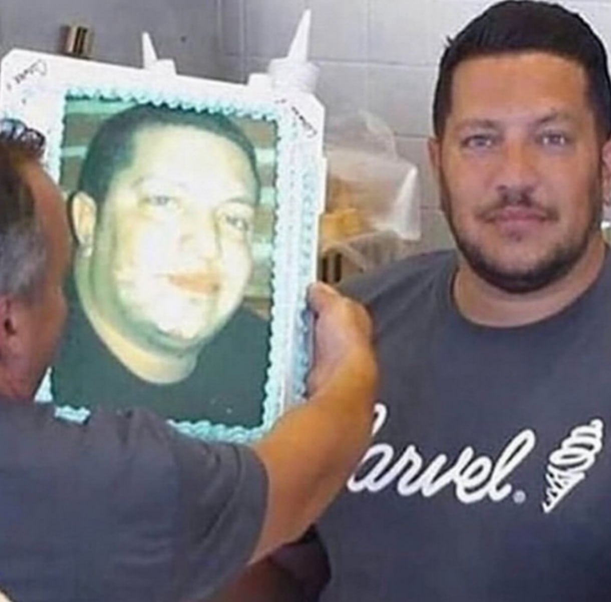 Мужчина держит торт со своей старой фотографией Мужчина держит квадратный торт с изображением своей старой, более полной фотографии, демонстрируя изменение внешности.