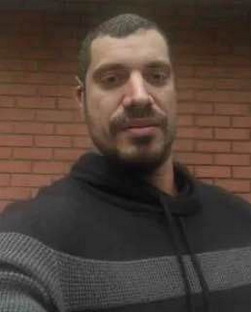 Мужчина в серой кофте Мужчина в сером свитере на фоне кирпичной стены.