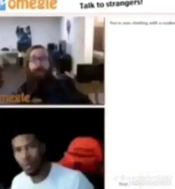 Мужчина в красной кепке на Omegle Мужчина в красной кепке, смотрящий на монитор во время видеозвонка на Omegle, с удивленным выражением лица.