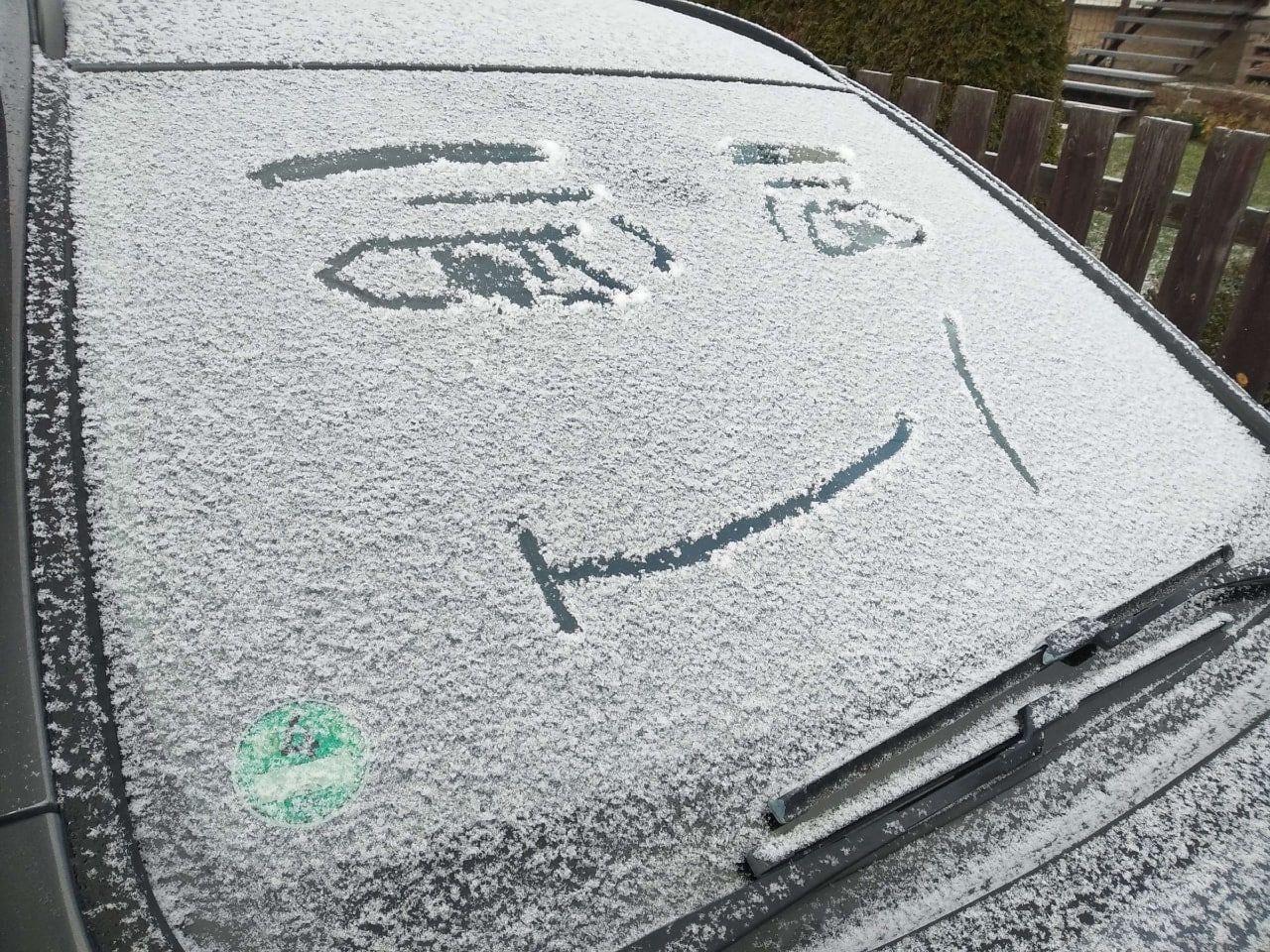 Машина улыбается Улыбающееся лицо, нарисованное на заснеженном лобовом стекле машины