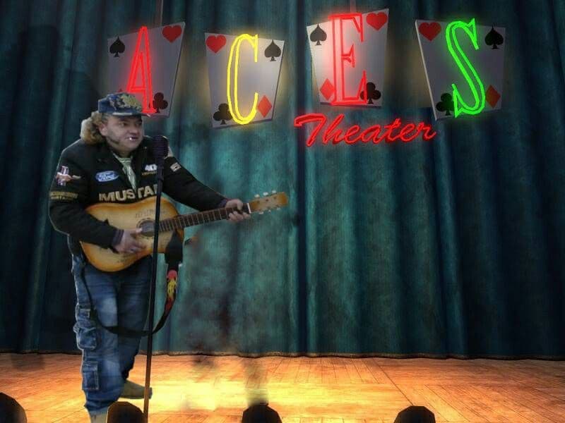 Мужчина на сцене Aces Theater Мужчина в кепке и куртке с нашивками играет на гитаре на сцене Aces Theater.