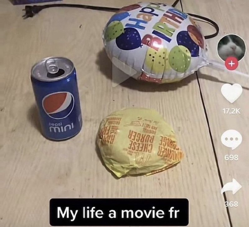 My life a movie fr На видео, оформленном как скриншот из ТикТока, изображен мини-обед, состоящий из банки Pepsi Mini, завернутого чизбургера и воздушного шарика с надписью «Happy Birthday». В углу виден круглый аватар с белой кошкой.