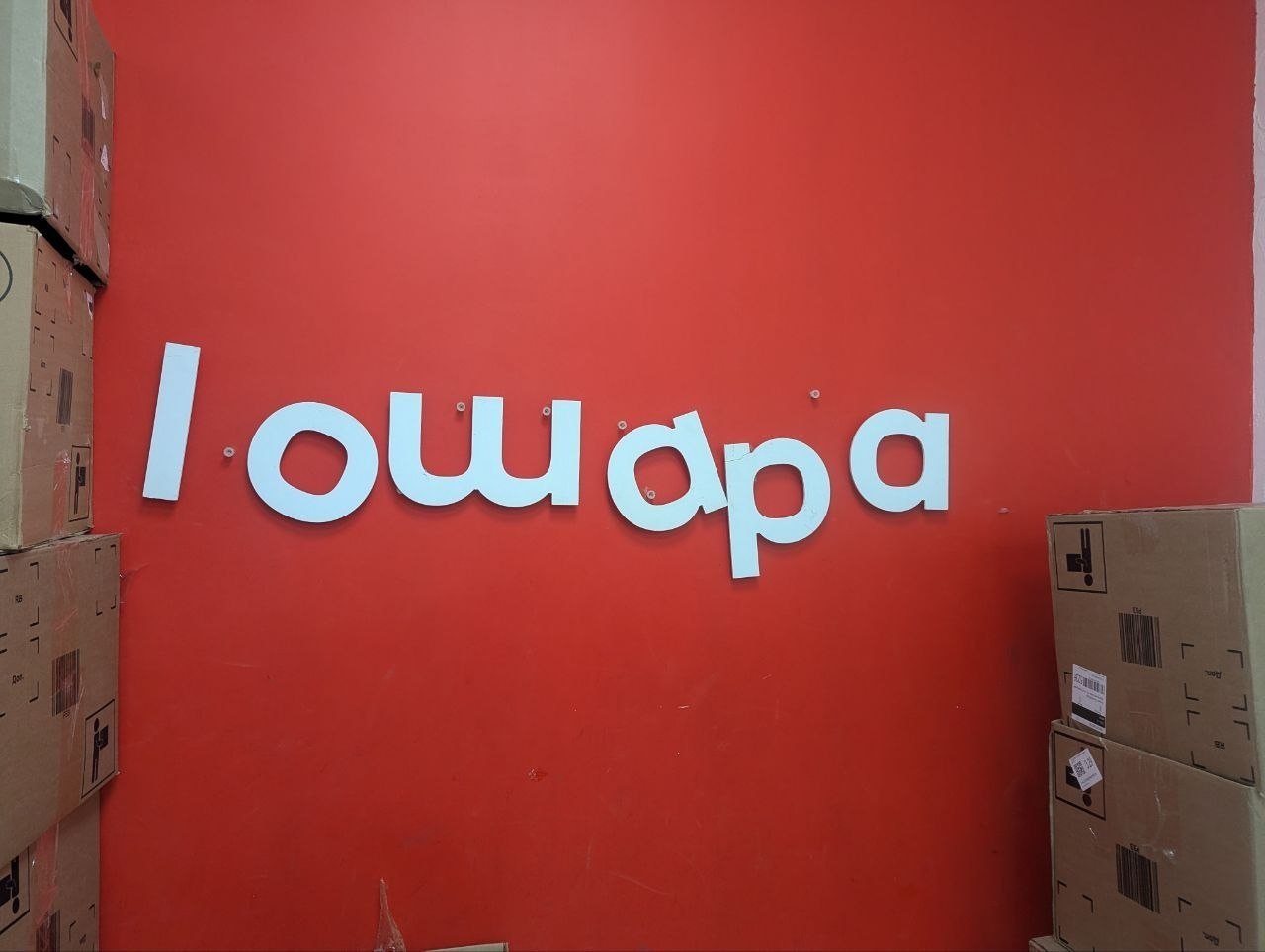 Красная стена с неровной объёмной надписью «loudpa» и коробками по бокам