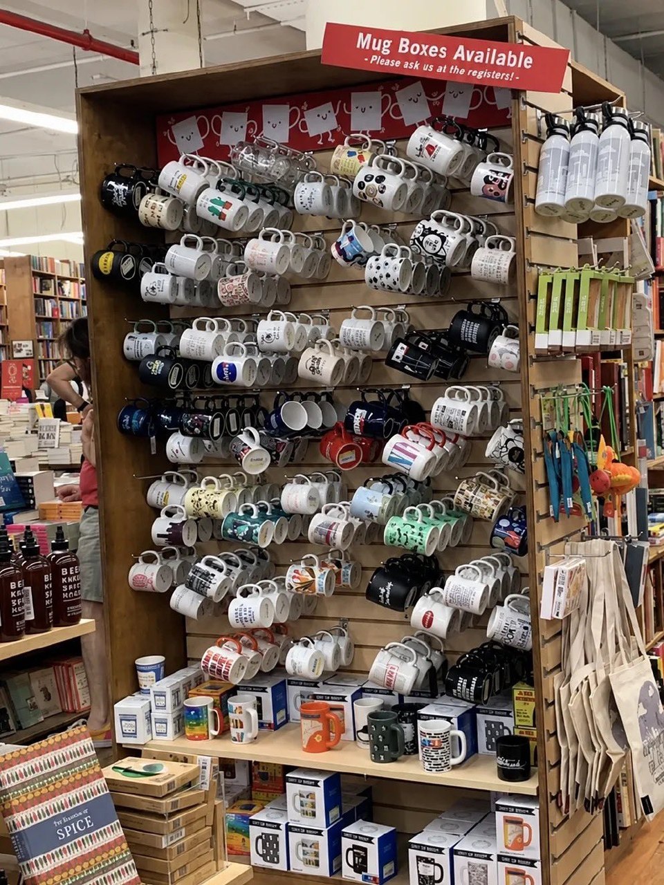 Стена с сотнями кружек в магазине и табличкой «Mug Boxes Available — Please ask us at the registers!»
