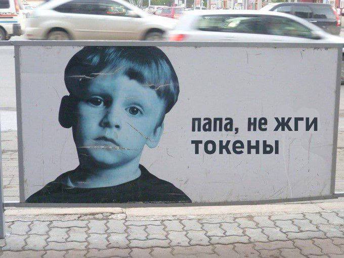 На уличном щите изображён грустный мальчик и надпись «папа, не жги токены».