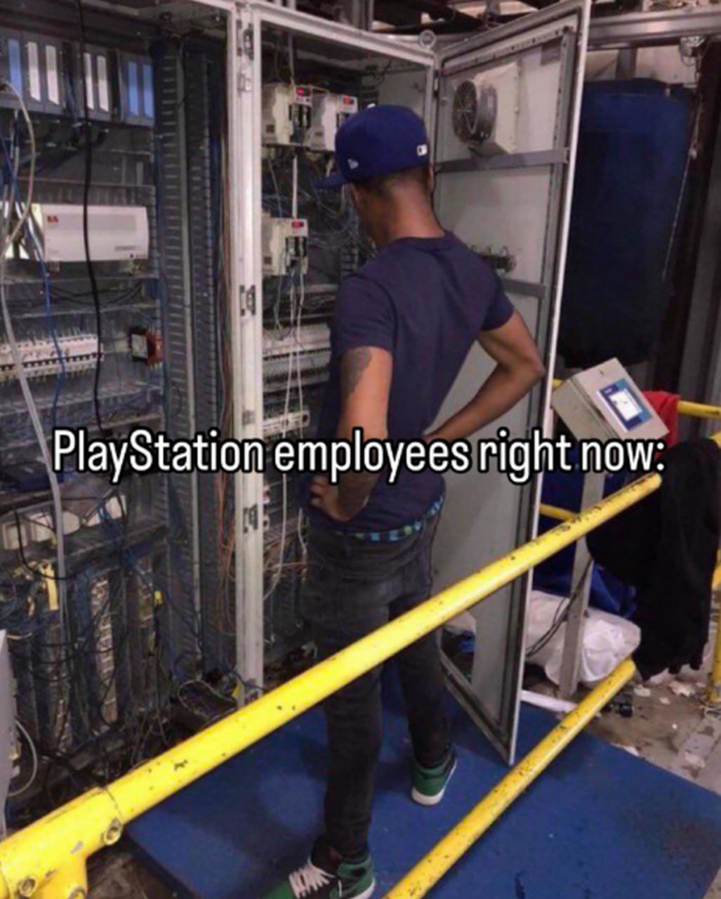 PlayStation employees right now Мужчина смотрит на запутанные провода в электрическом щитке с надписью «PlayStation employees right now»