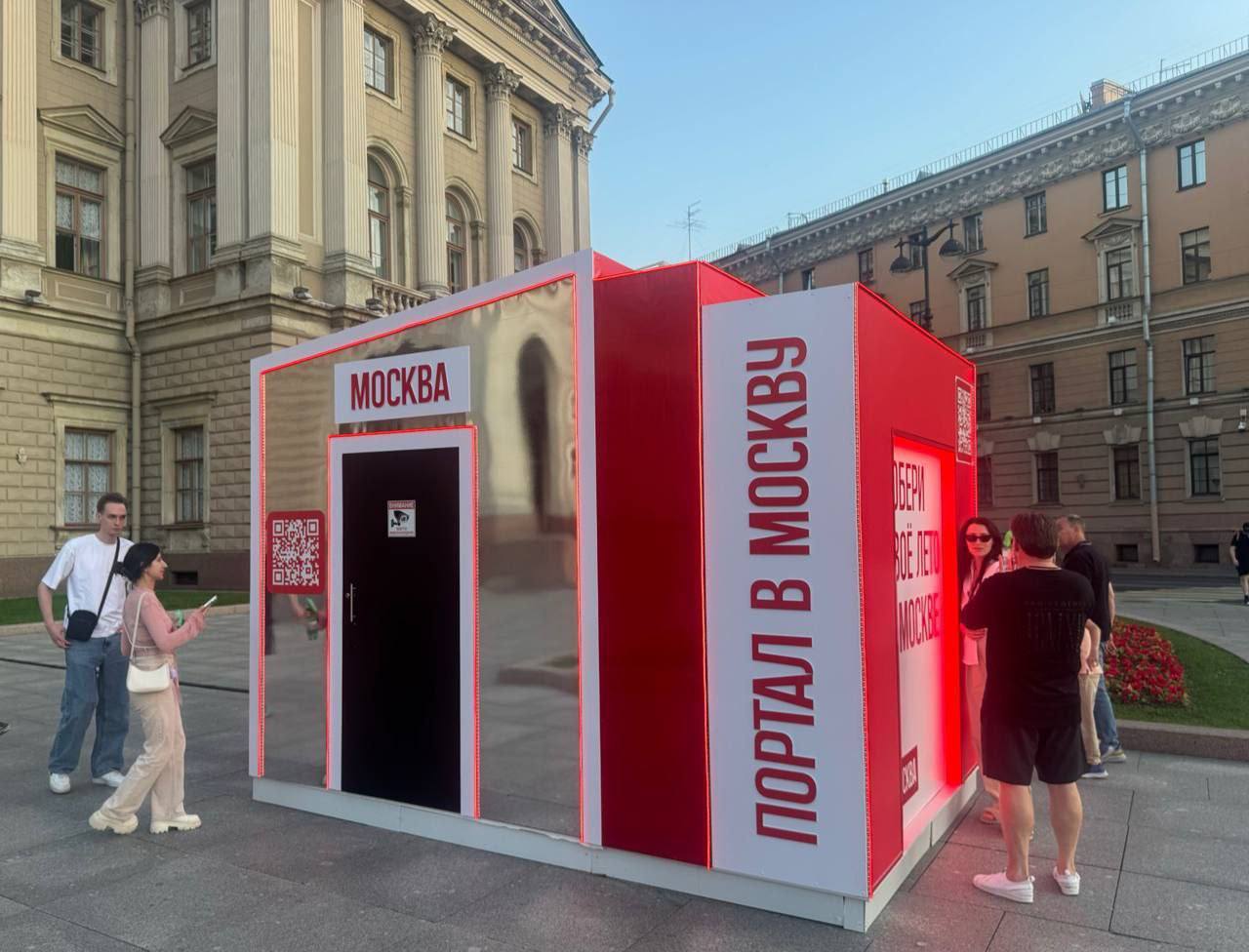 Портал в Москву Красный киоск с зеркальными поверхностями и надписями "Москва" и "Портал в Москву" на улице.