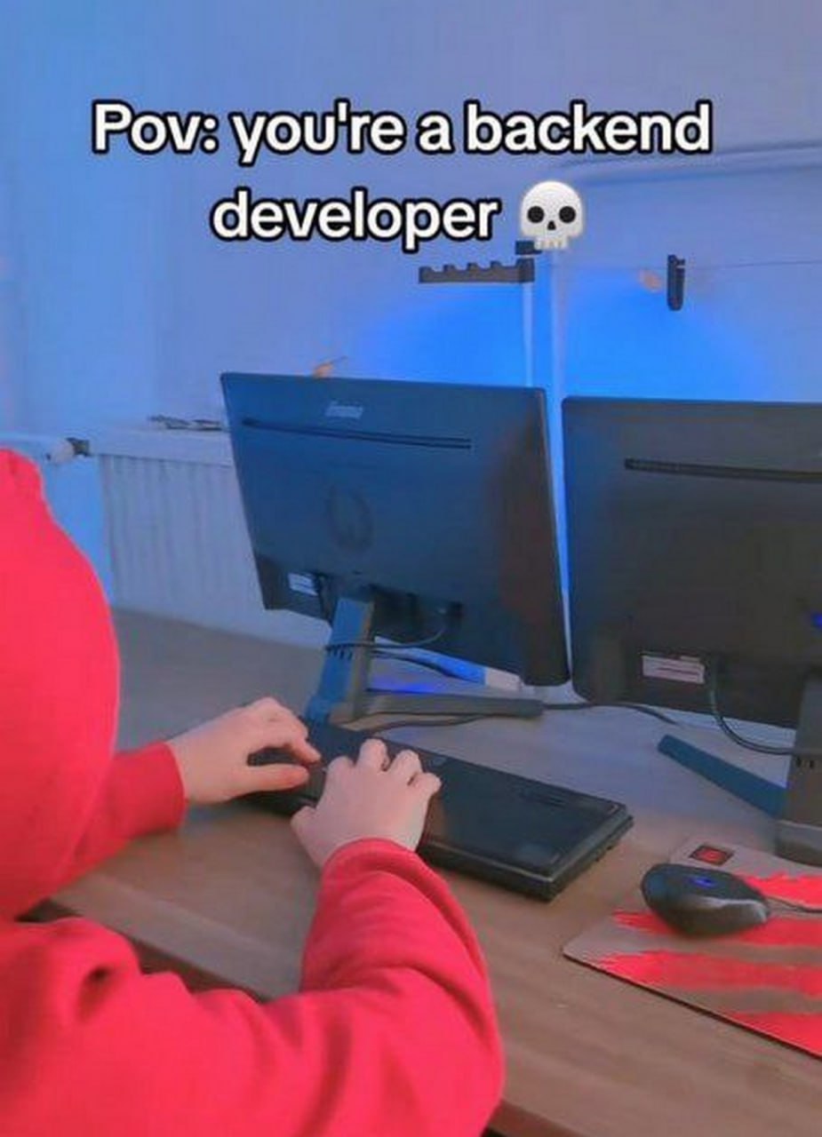Pov: you're a backend developer Мем, где человек в красном худи сидит за компьютером с двумя мониторами и пишет код, а надпись гласит "Pov: you're a backend developer"