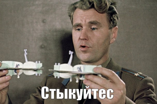 Прицелитесь Мем, где человек в военной форме держит в руках две модели космических кораблей, сделанные из купюр, и говорит: "Прицелитесь" (Стыкуйтесь)